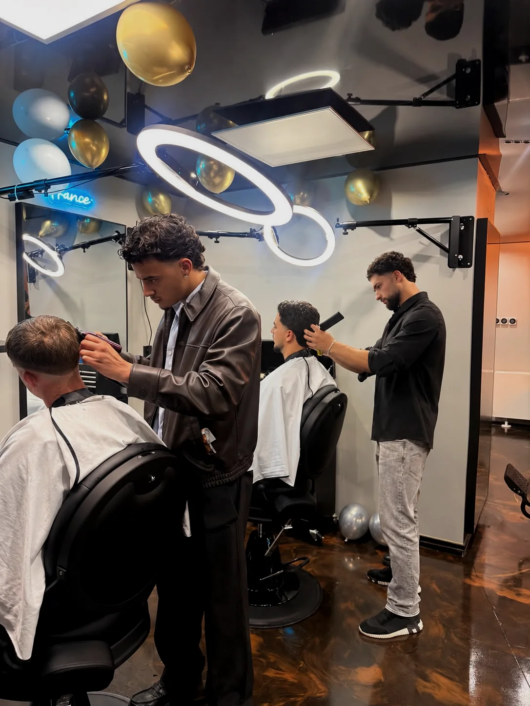 Zwei Barber von HOCHHEIMERS beim Haarschnitt unter den Ringleuchten im Salon